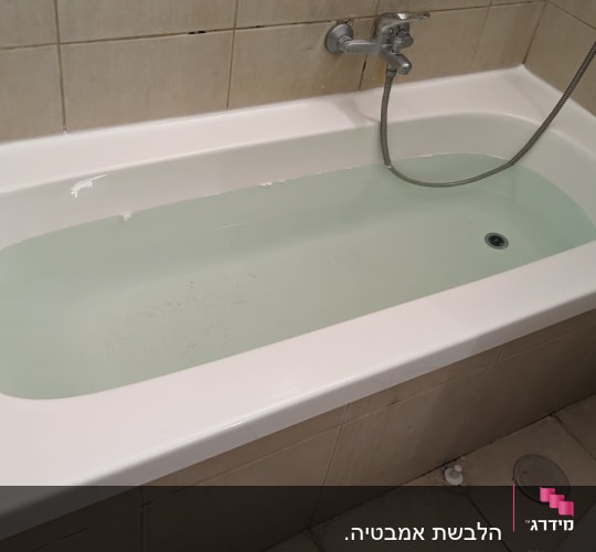 אמבטיה מלאה במים עם ברז ומקלחת יד
